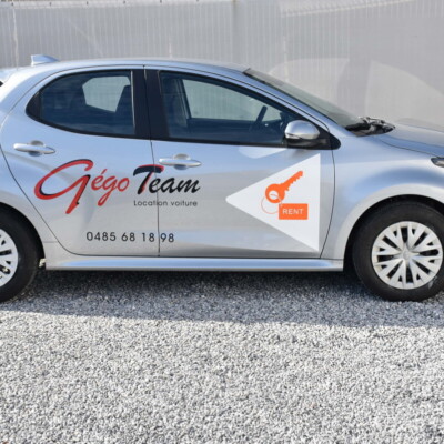 Vue latérale d'une voiture Toyota Yaris grise avec un logo GégoTeam