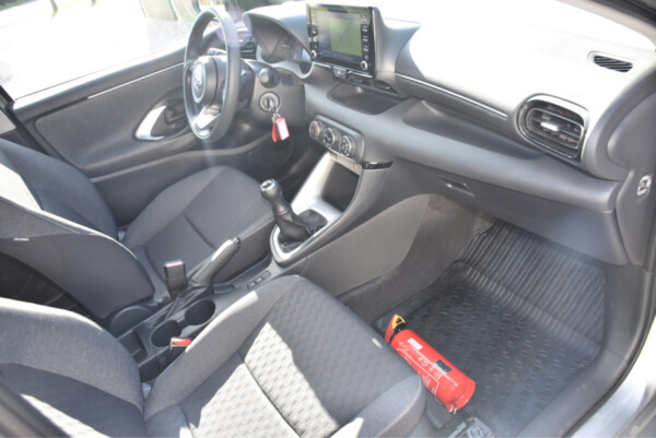 Vue de l'intérieur de la cabine d'une Toyota avec un volant multifonctions, un écran tactile central et des sièges en tissu